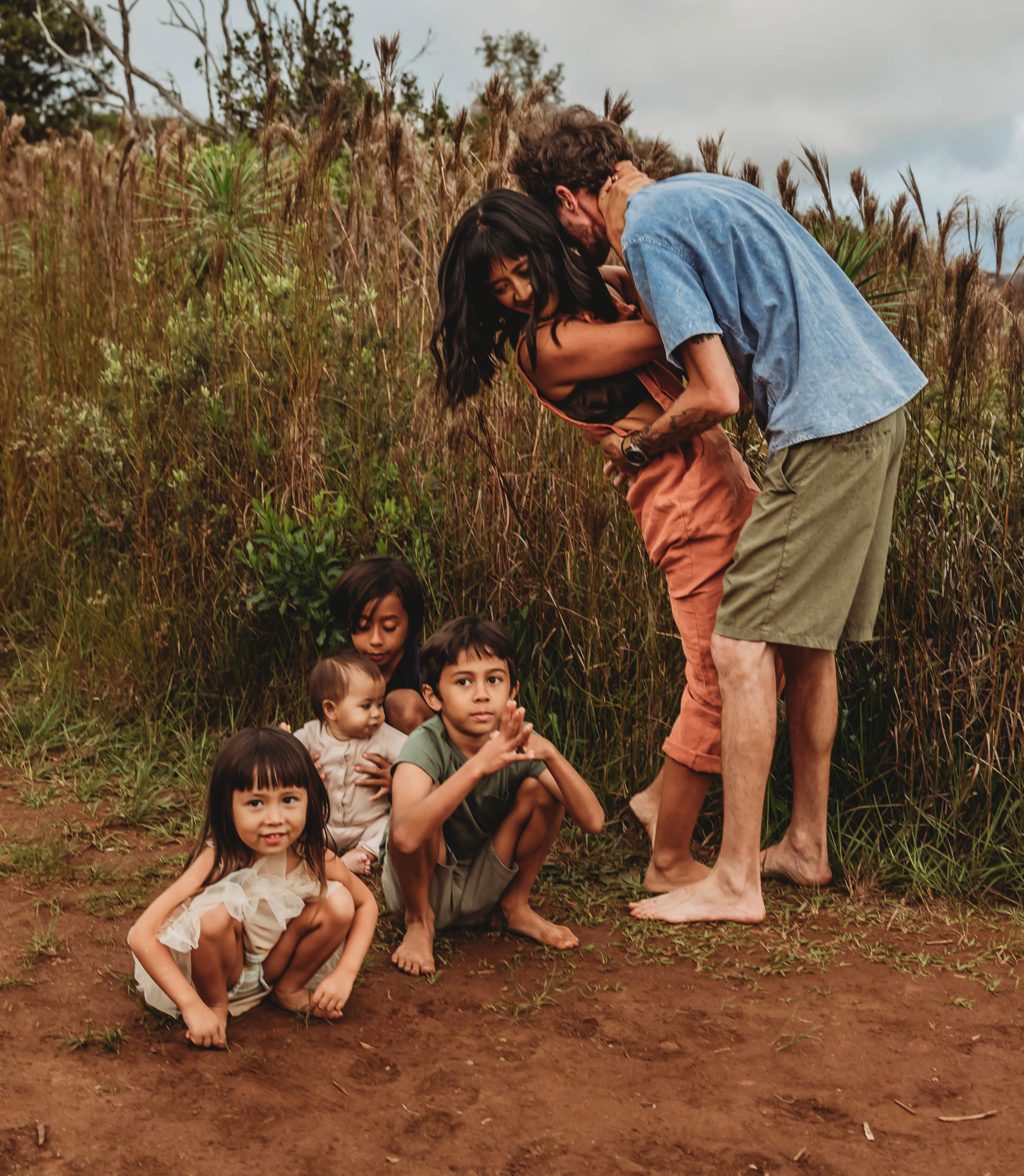 Family hugging in front of Waimea Canyon red cliffs