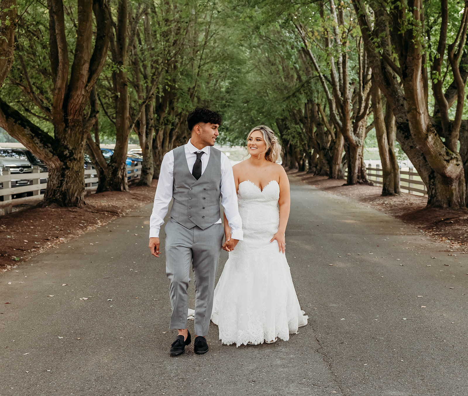 Bride and groom walking hand in hand at the tree-lined entrance road of Maplehurst Farm in Mount Vernon, WA — a favorite among Wedding Venues Bellingham Skagit.