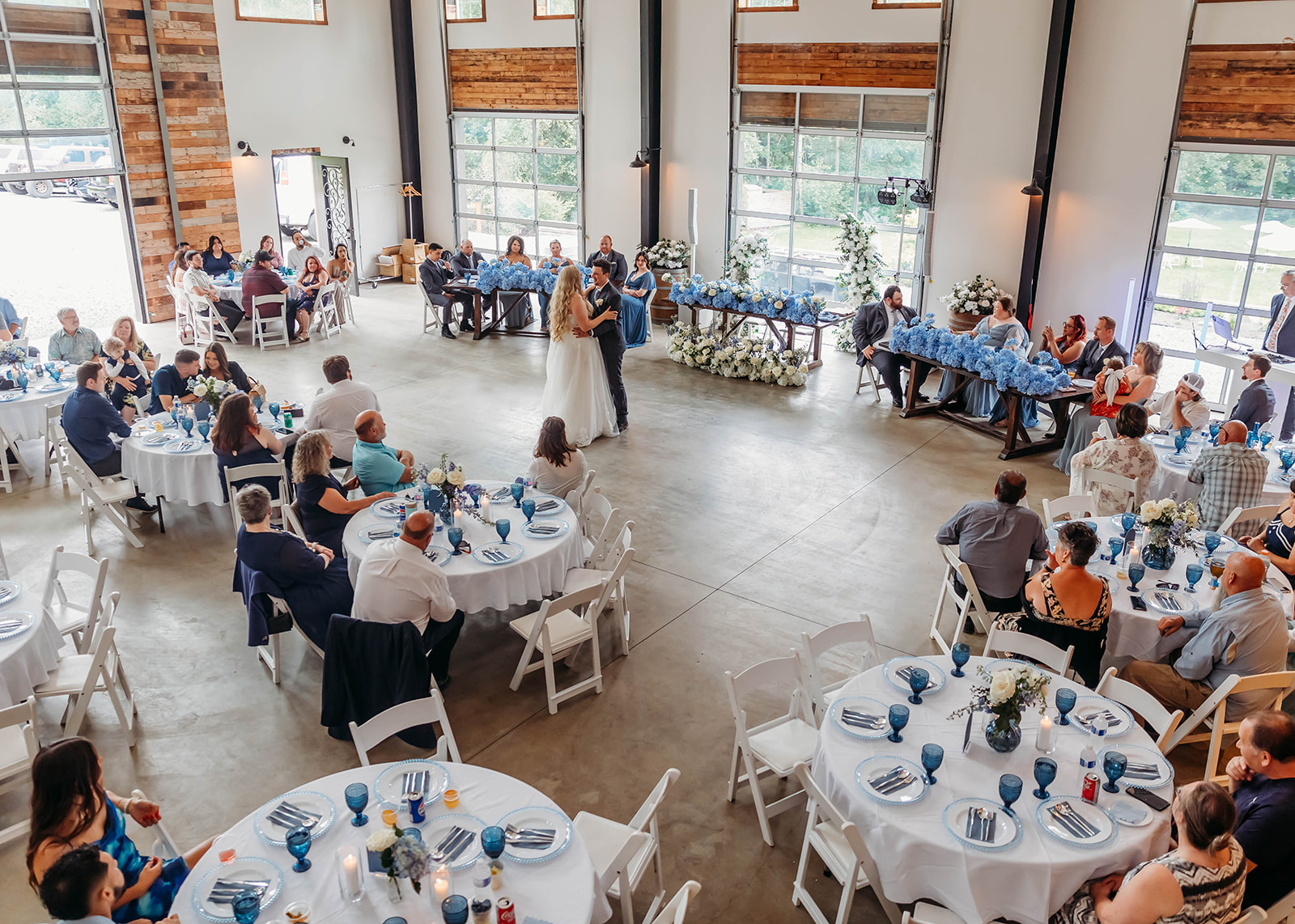 Wedding reception at Carson Creek Estate in Bellingham WA with bride and groom sharing their first dance in a modern barn-style venue surrounded by guests and blue floral decor — one of the top Wedding Venues Bellingham Skagit.