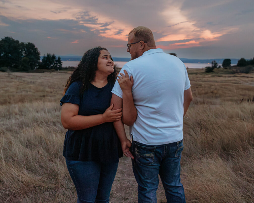 Interracial couple walking and laughing together along a natural trail at Discovery Park during golden hour.