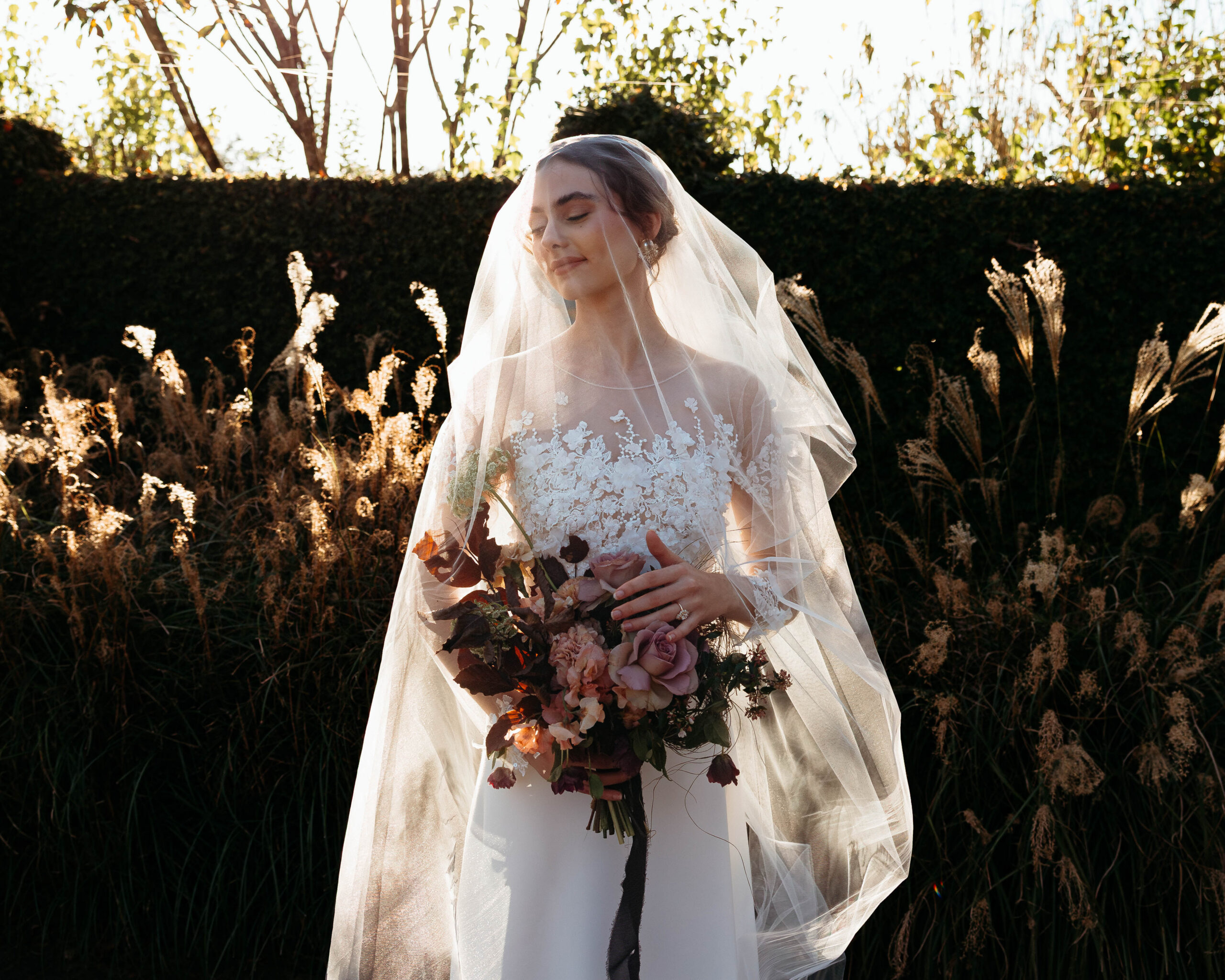 Bride holding bouquet under veil during North Carolina garden wedding at Britton Manor with golden hour lighting