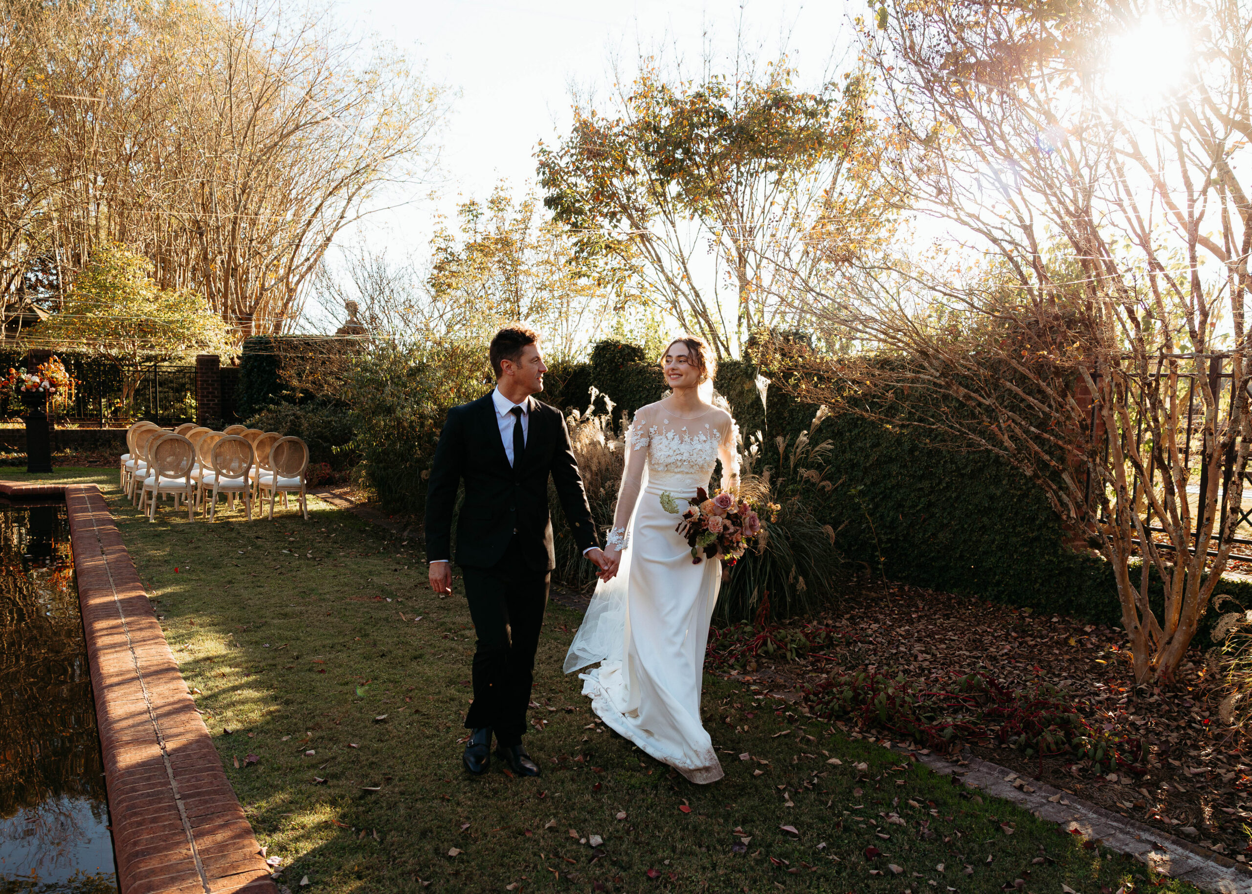 Couple walking hand in hand during Britton Manor wedding in Raleigh North Carolina with warm sunset light and garden ceremony space